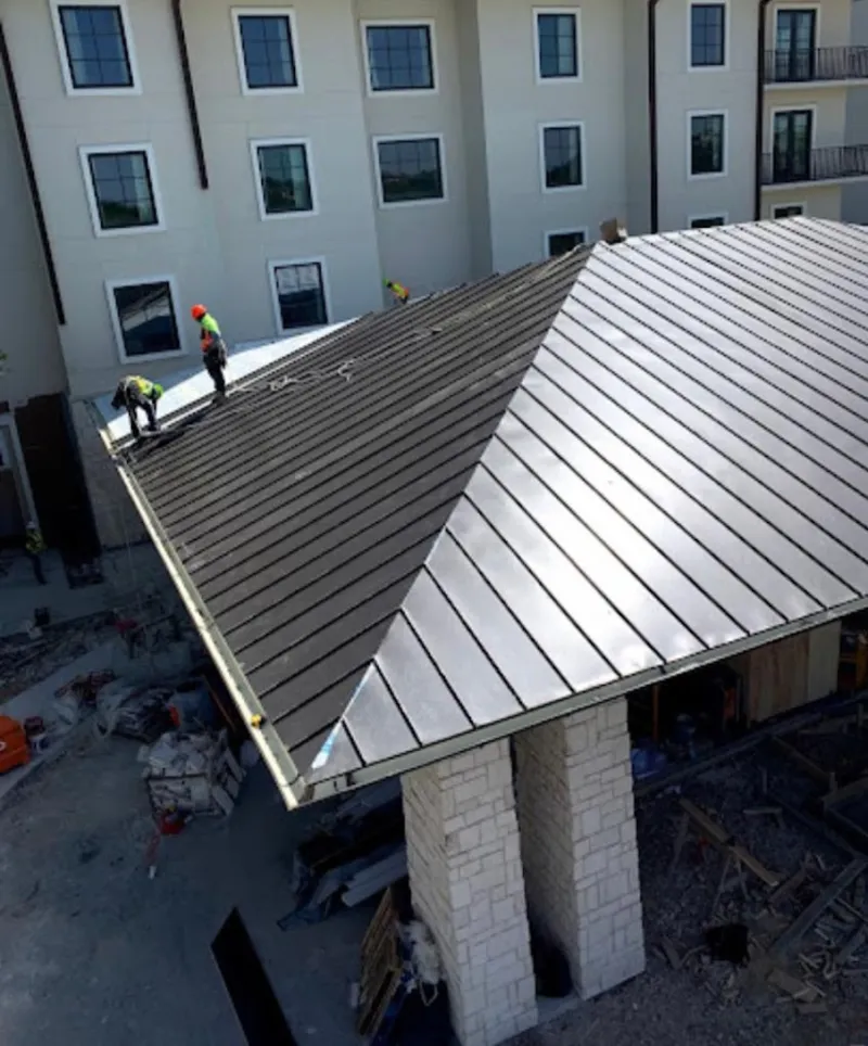 Crew installing standing seam metal roof panels on a commercial project in Four Corners